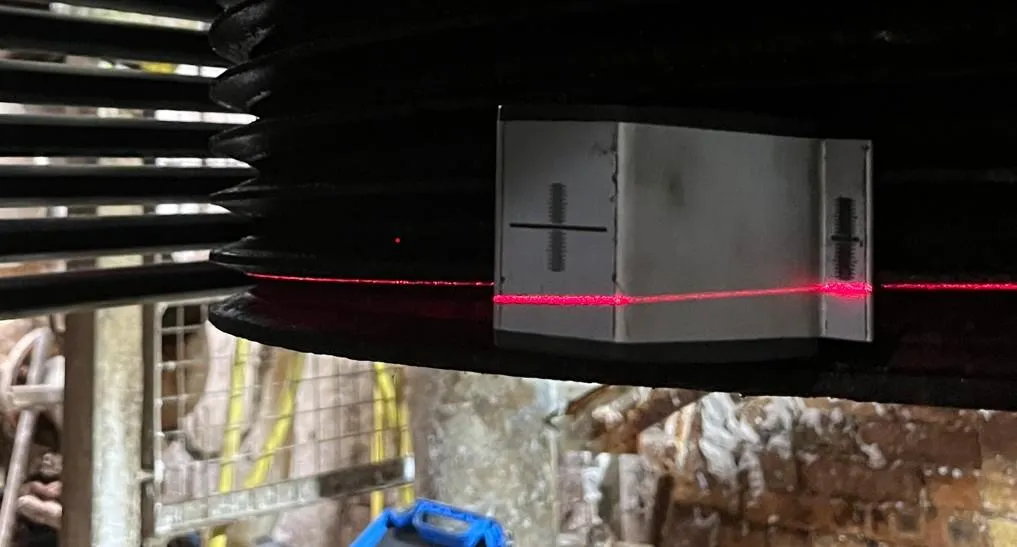 A laser alignment tool set across drive pulleys, showing the misalignment recorded at the shaft.