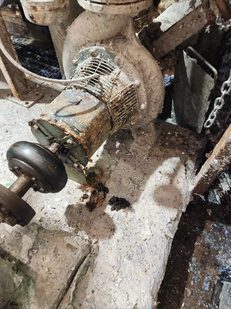 A pump and motor recorded as found, heavily fouled with dried stock, the coupling and shaft exposed.