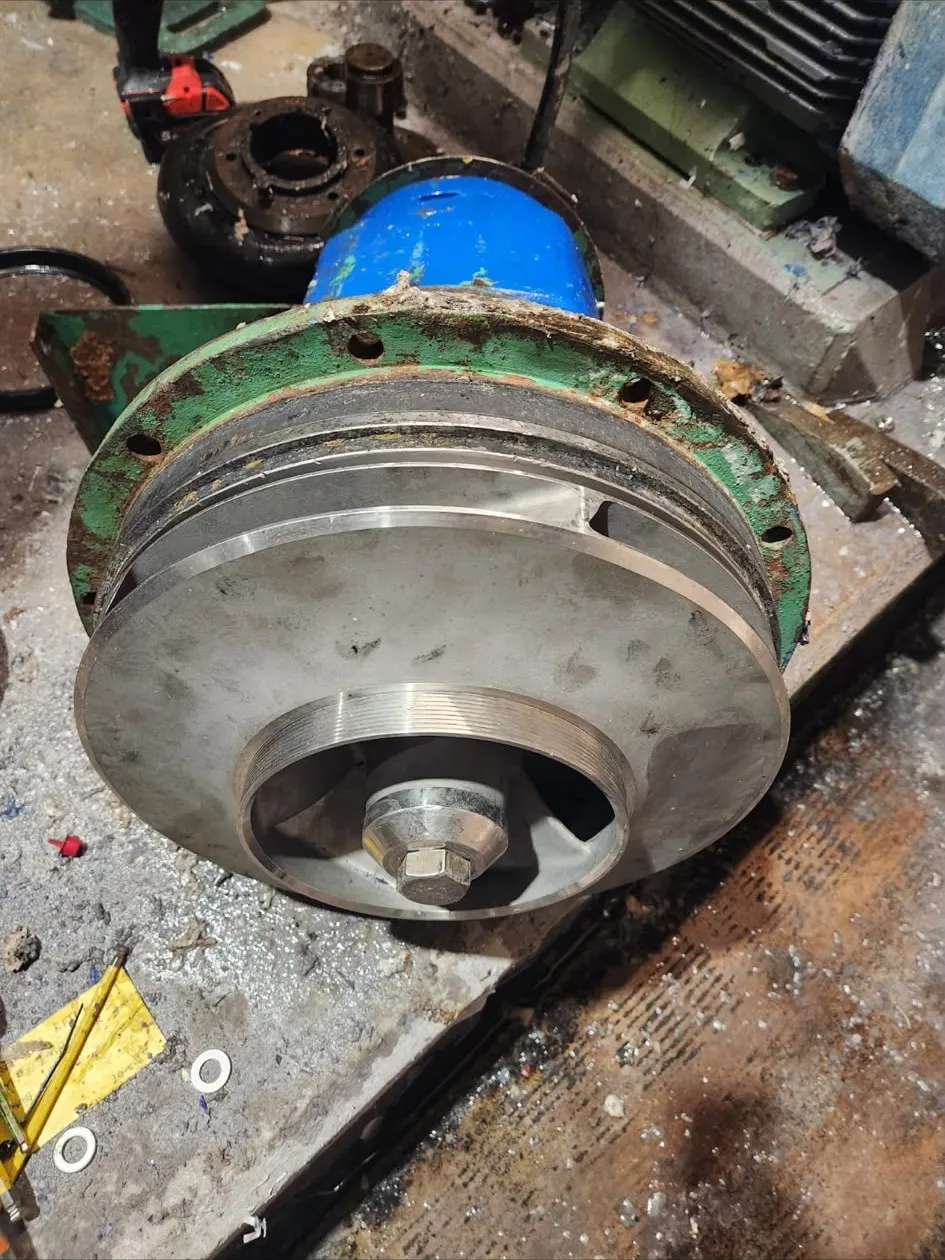 A pump rotating assembly withdrawn onto a bench, the closed impeller and wear ring visible inside the casing cover.