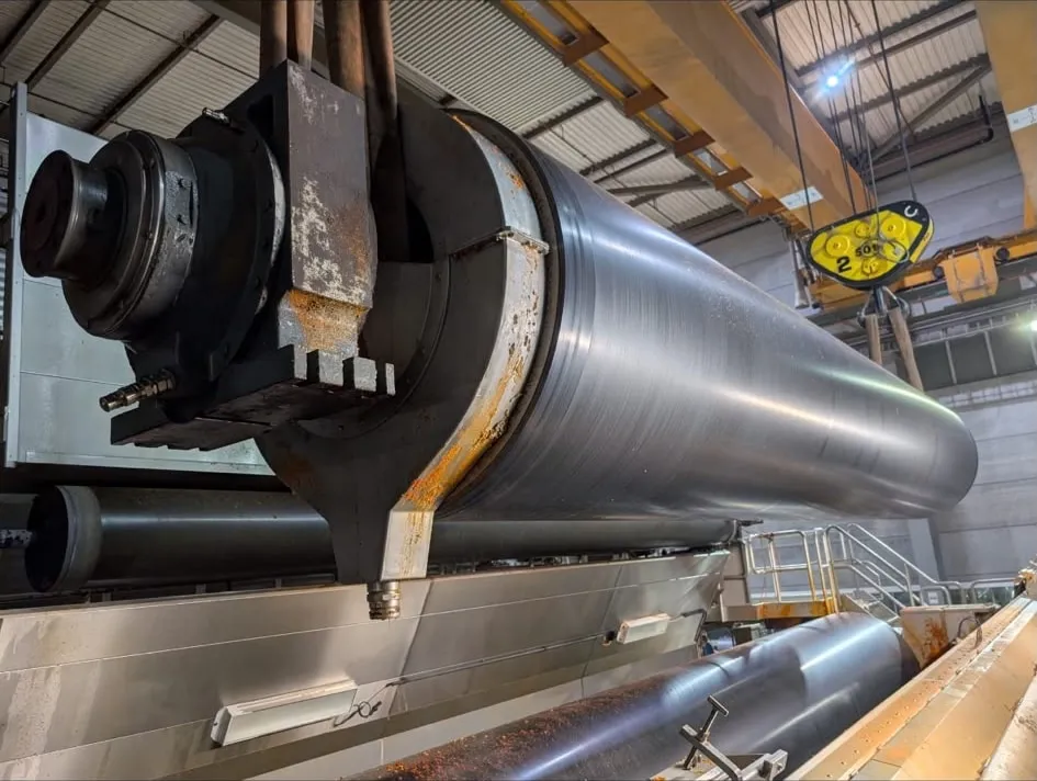 A machine roll suspended horizontally on chain hoists, bearing journal exposed.