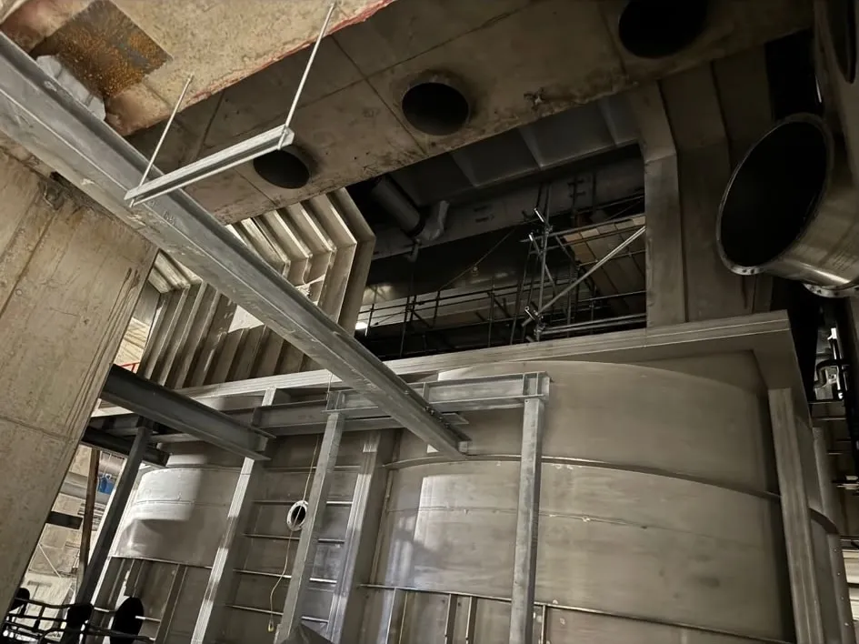 Looking up into fabricated stainless steel ductwork and pipework inside a plant.